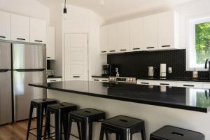 Una cocina con gabinetes blancos y encimeras negras. en Spa and Lakefront - Oasis des chutes, en Lac-Saint-Paul 33 fotos más