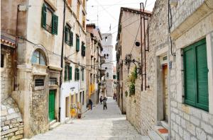 an alley with people walking down a street at Light filled spacious penthouse in Šibenik city centre in Šibenik