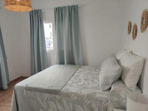 a bedroom with a bed with blue curtains and a window at Maresía La Santa in La Santa