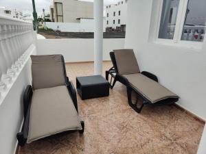 two chairs and a stool sitting on a balcony at Maresía La Santa in La Santa