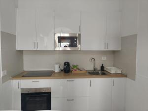 a white kitchen with a sink and a microwave at Maresía La Santa in La Santa