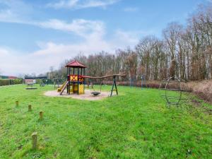 un parc avec une aire de jeux avec un toboggan et des balançoires dans l'établissement Holiday Home in Noordwijkerhout near Lake, à Noordwijkerhout
