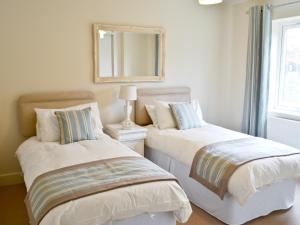 zwei Betten in einem Zimmer mit einem Spiegel an der Wand in der Unterkunft Salar's Rest - 28028 in Alnmouth