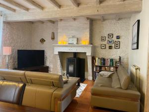 a living room with a couch and a fireplace at Le relais de l'ancienne poste in Sigoulès
