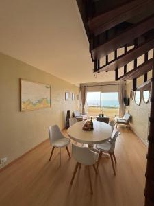una sala de estar con una mesa y sillas en Duplex vue mer à Rochebonne Plage Parking, en Saint-Malo