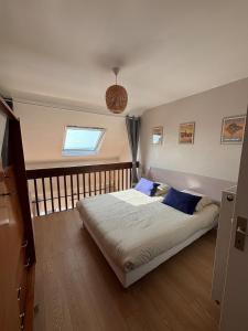 Un dormitorio con una cama con almohadas azules y una ventana. en Duplex vue mer à Rochebonne Plage Parking, en Saint-Malo
