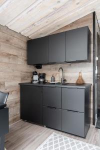 a kitchen with black and white cabinets and wooden walls at Himosranta Suite A - Private Suite with Hot Tub & Lake Views in Jämsä
