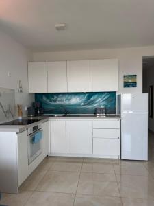 a kitchen with white cabinets and a painting on the wall at Apartment „Blue“ in Mandre