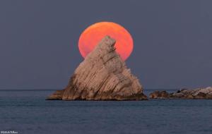 an orange moonrise over an island in the ocean at La Fabbryca in Porto SantʼElpidio