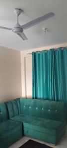 a green couch in a living room with a blue curtain at N&G Blessed Pioneer Holiday Homes in Mombasa +1 photo
