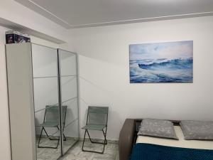 a bedroom with two chairs and a bed and a painting at Cozy Studio - Vue Mer Magnifique in Roquebrune-Cap-Martin