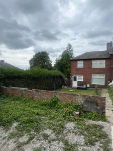 a brick house with a retaining wall in the yard at Luxeliving The Larch Residence in High Hazels