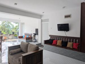 a living room with a couch and a tv on a wall at White Lotus Haputale in Haputale