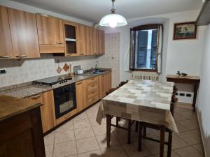 a kitchen with wooden cabinets and a table in it at L'Appartamento d'Elda in Santa Maria Maggiore