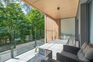 un patio esterno con divano e sedie su un balcone di Forest by Solarento a Międzyzdroje