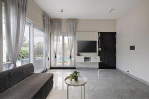 a living room with a couch and a tv at The Garden Stay by StayJadePool2BHKLawnAC in Berikai