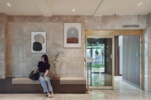 a woman sitting on a bench in a lobby at Hotel Yaja Mokpo Peace Square in Mokpo