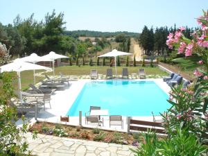 a large swimming pool with chairs and umbrellas at Villa Madeleine Tower View in Nea Fokea