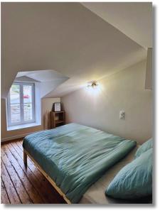 a bedroom with a large green bed in an attic at Maison 2-5 pers au calme proche Parc in La Pommeraie-sur-Sèvre