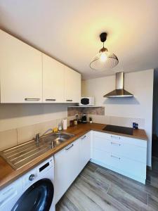 a kitchen with white cabinets and a sink at Maison 2-5 pers au calme proche Parc in La Pommeraie-sur-Sèvre
