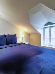 a bedroom with a large blue bed with a window at Maison 2-5 pers au calme proche Parc in La Pommeraie-sur-Sèvre