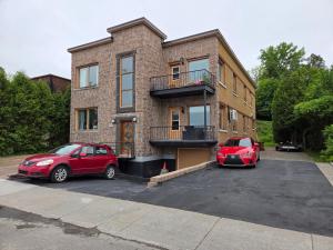 two cars parked in a parking lot in front of a building at Chambre chez Martin in Saguenay