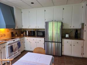 a kitchen with white cabinets and a stainless steel refrigerator at Chambre chez Martin in Saguenay