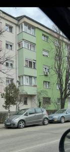 two cars parked in front of a green building at Relax Loft in Oradea
