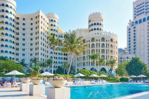 a hotel with a swimming pool in front of tall buildings at Private Suites Al Hamra Palace at golf & sea resort in Ras al Khaimah