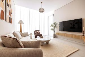a living room with a couch and a tv at District One Dubai Lagoon View Near Downtown in Dubai