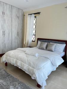 a bedroom with a large bed with white sheets at MoDi's Seaside Nest in Mombasa +18 photos