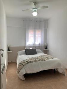 Un dormitorio blanco con una cama y un ventilador de techo. en Mejorana Habitaciones, en Madrid