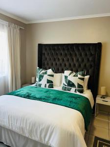 a bedroom with a large bed with green and white pillows at Apartment with stunning scenic views in Pretoria