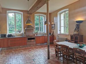 eine Küche mit einem Tisch und einigen Fenstern und einem Tisch und Stühlen in der Unterkunft Château Seguier - Loire Valley and vineyards in Brinon-sur-Sauldre