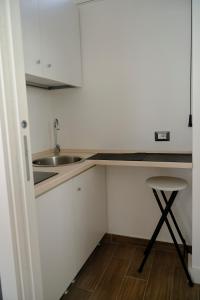 a kitchen with white cabinets and a sink and a stool at La Casa Di Giove in Terracina