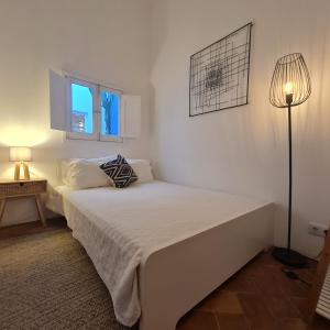 a white bedroom with a bed and a lamp at Lavadeira's House in Olhão