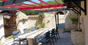 a wooden table and chairs under a red roof at Le Val des Nymphes in Colonzelle