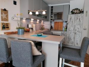 une cuisine avec une île entourée de chaises dans l'établissement Paula - gemütliche Maisonette auf Fehmarn, à Fehmarn 8 autres photos