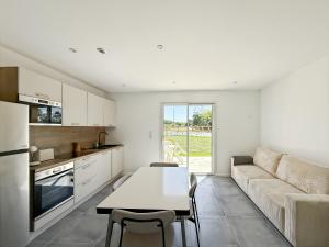 a kitchen and living room with a table and a couch at La Maisonnette - Jardin & Calme in Saint-Ouen-des-Alleux