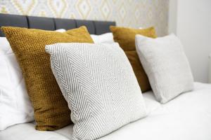 a pile of pillows on a bed with white and brown pillows at Devon Hot Tub Retreat in Bideford