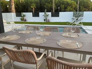 a table with wine glasses and chairs on a patio at Esmeralda Sea Villa - Beach&Golf Sancti Petri in Novo Sancti Petri