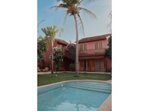 a palm tree and a house with a swimming pool at Gorée Suites in Saly Portudal