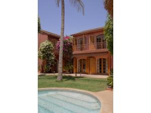 a house with a palm tree and a swimming pool at Gorée Suites in Saly Portudal