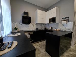 a kitchen with a black counter and white cabinets at Apartament in Legnica