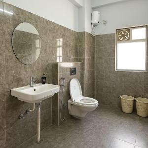 Un baño con inodoro, lavabo y espejo. en The Aura 2BHK near Paltan bazar, en Guwahati