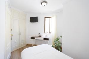 a white bedroom with a bed and a desk at Hostal San Miguel by Croma in Estepona