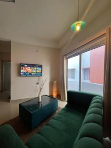 Una sala de estar con un sofá verde y un televisor. en The Aura 2BHK near Paltan bazar, en Guwahati