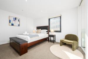 メルボルンにあるFoundry Top Floor 2BR Loft Parking & Workspaceのベッドと椅子と窓のある寝室