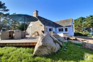 a house with a large rock and an umbrella at La maison bleue in Trégastel