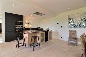 a kitchen with black cabinets and bar stools at A l'abri des pins in Pleubian